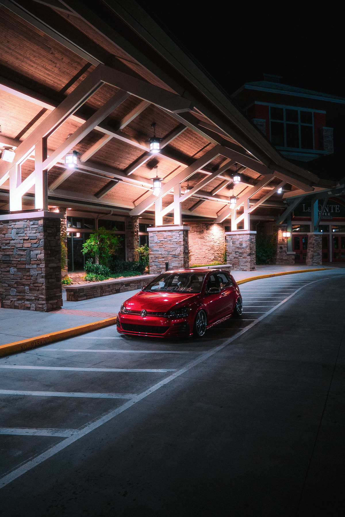 Digital still, a red hatchback under lights at night